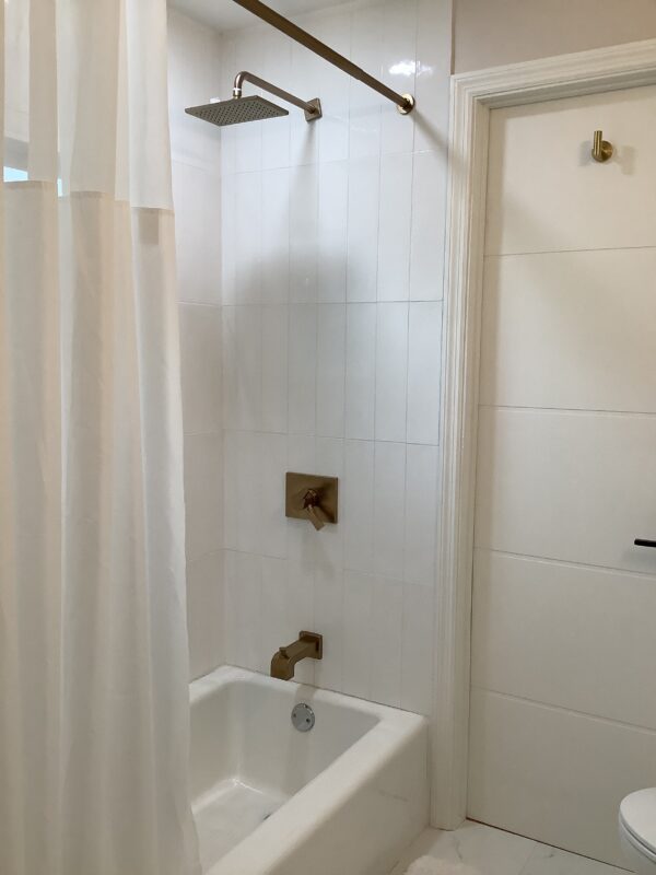 A bathroom with white tile and a tub.